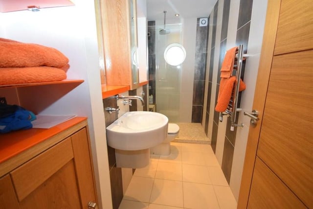 Here is the smart en suite shower room by the bedroom on the ground floor. It comprises a double shower cubicle, low-flush WC and wash basin with storage surround. A polished, tiled floor, underfloor heating and characterful circular window add to its style.