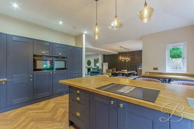 Integrated appliances within the kitchen include an eye-level double oven, while the central island features an integrated hob.