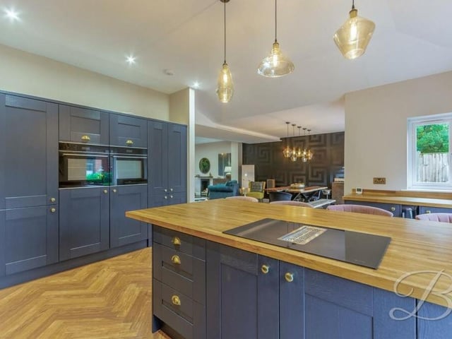 Integrated appliances within the kitchen include an eye-level double oven, while the central island features an integrated hob.