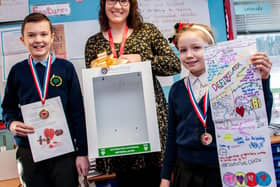 Greenwood Primary &amp; Nursery School children Oliver Parkin and Athena Ashford with Holly Younger
(centre) and the new cabinet for the school’s defibrillator.