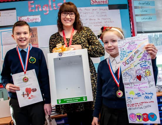 Greenwood Primary &amp; Nursery School children Oliver Parkin and Athena Ashford with Holly Younger
(centre) and the new cabinet for the school’s defibrillator.