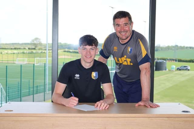 Goalkeer Frankie Shepherd signs his pro contrract with Mansfield Town as manager Nigel Clough watches on.