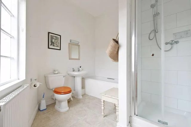 The bathroom is a generous size, having a white panel bath, a separate shower enclosure, a wash basin, WC, finished with splash-back tiling, and a tiled floor.