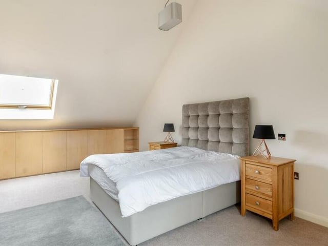 The final bedroom at the £700,000 Sutton property is another large double with a high vaulted ceiling. Facing the front of the house, it includes custom-fitted maple-oak storage cabinets on both sides of the room, as well as an under-window seat. A door gives access to a loft space.