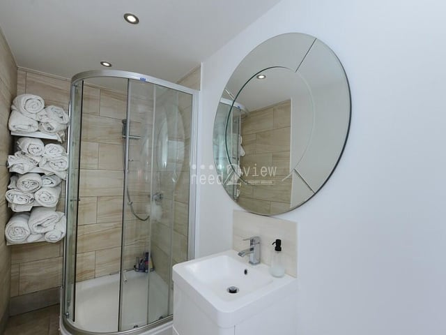 The master bedroom and its extension have access to this en suite shower room. It is made up of a shower cubicle, wash hand basin, built into a vanity unit, WC, partly-tiled walls and ceiling spotlights.