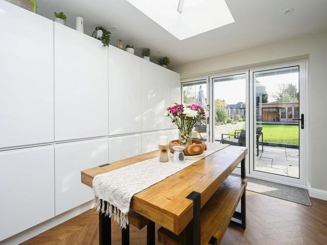 The dining room features a range of smart wall units, and also bifold doors that lead to the back garden, with its patio area.