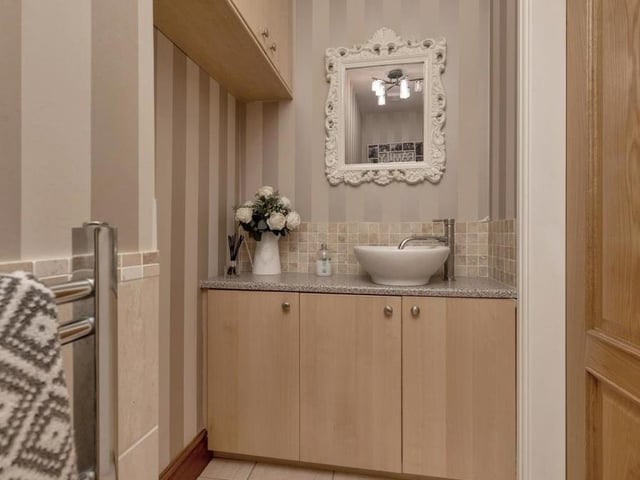 This cute-looking toilet completes our tour of the ground floor. It consists of a two-piece white suite with a low-flush WC and a wash hand basin mounted on a worktop with storage cupboards beneath. There is also an overhead storage cupboard and a chrome, heated towel-rail.