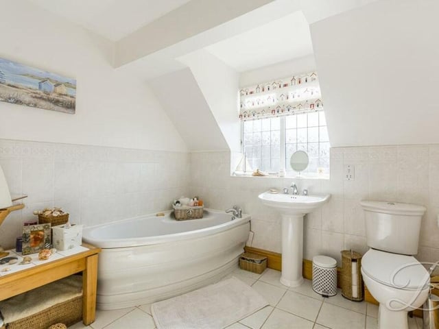 The family bathroom completes our look at the interior of the property. It is a three-piece suite in white, consisting of a panelled corner bath, a low-level WC and pedestal hand wash basin. The floor is tiled.
