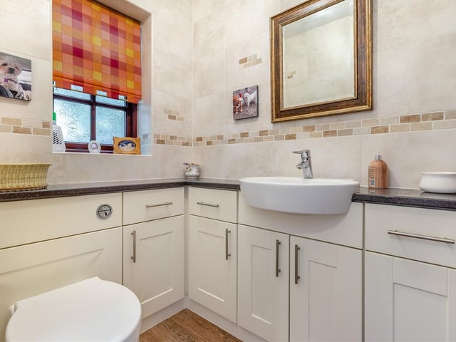 A handy addition to the ground floor is this cloakroom/toilet. A contemporary two-piece white suite comprises a low-flush WC and large vanity unit with inset wash hand basin and chrome mixer tap, work surfaces to each side and storage cupboards and drawers beneath. The walls are fully tiled.