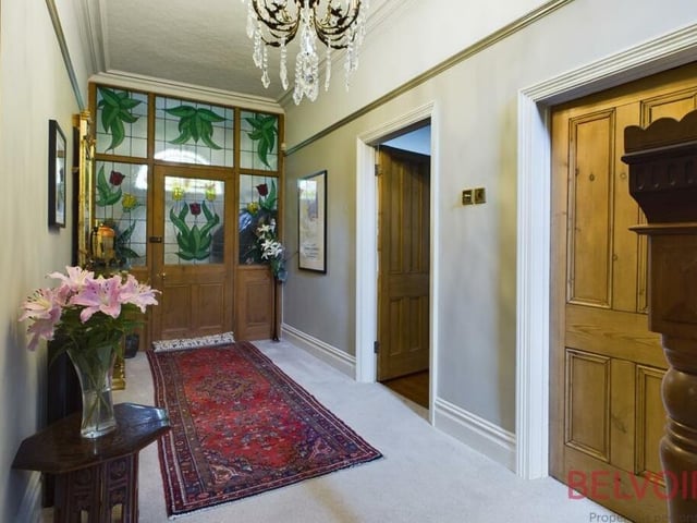 This welcoming and grand entrance hallway guides you to the rooms on the ground floor of the house. It features stained glass windows, a chandelier, two cast-iron radiators and an under-stairs cupboard.