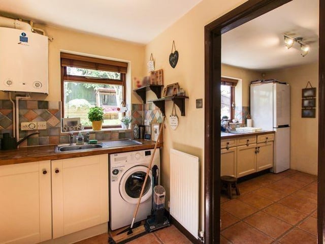 Through the kitchen archway and into this utility room, which has base units matching the kitchen, work surfaces over, and a stainless steel sink and drainer. There is also tiled flooring and plumbing for a washing machine.