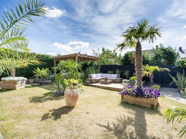 The garden is predominantly laid to lawn and framed by a secure fence surround, offering privacy and space for outdoor enjoyment. Thoughtfully landscaped, it includes established palm trees, a raised decked area and a patio seating area complete with a pergola.