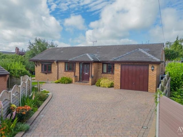 At the front of the bungalow, a large, block-paved driveway has off-street parking space for four or five cars and leads to a garage.