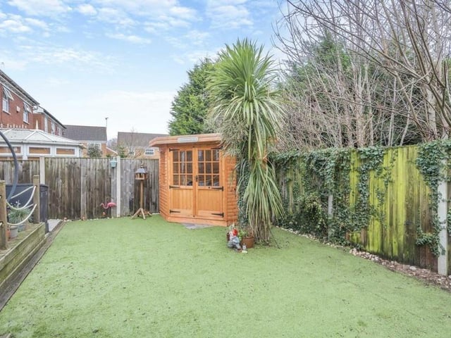 A lawn of artificial turf ensures that the landscaped back garden is low maintenance. It leads to a cute summer house.
