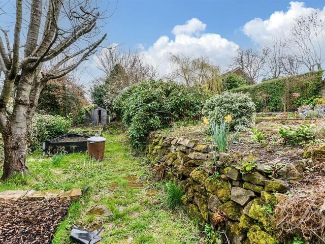 At the rear, you'll discover a beautifully landscaped garden, featuring a spacious lawn, mature shrubs, a decorative pond, and a lovely decked seating area.