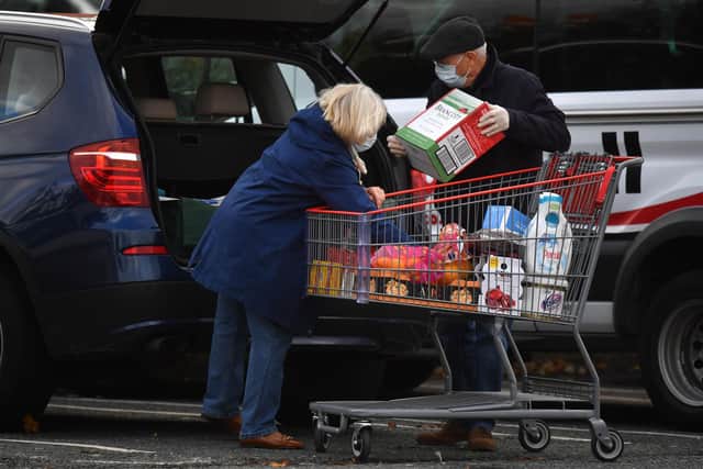 Shoppers load their car after purchasing items from a Costco store (Photo by Ben STANSALL / AFP)