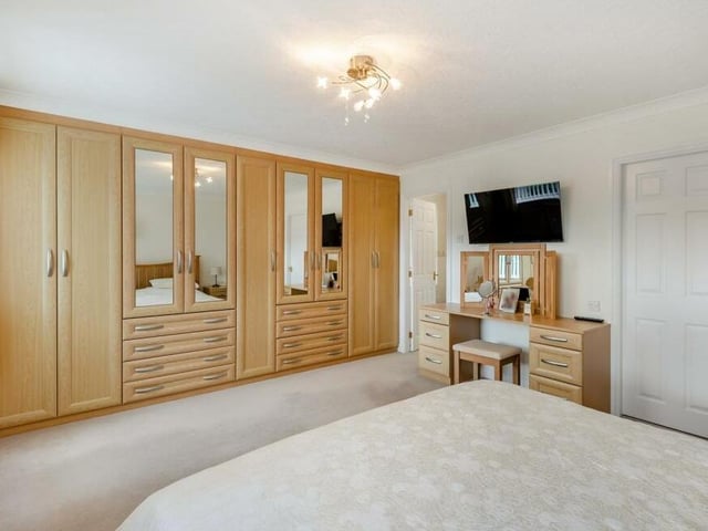 Extensive fitted wardrobes line one wall of the master bedroom, complete with hanging rails, shelving and eight drawers.