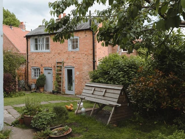 A view from the back of the property, showing the garden, which houses the secondary cottage. The garden is made up of lawn, deep flowerbeds and a small kitchen garden.