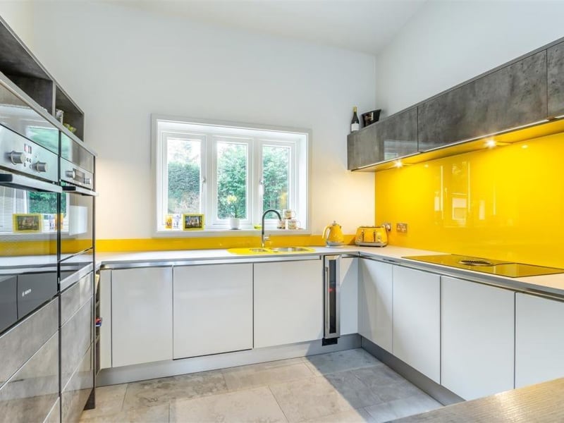 The sleek dining kitchen sparkles with a range of high-gloss, modern cabinets. Integrated appliances include a Bosch oven and microwave combi-oven, warming drawer, Elica downdraught induction hob, wine cooler, fridge, freezer and dishwasher. There's also a stainless steel sink-and-a-half with swan-neck mixer tap and drainer.
