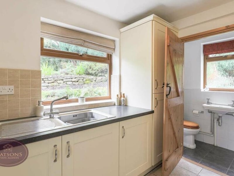 Close to the dining kitchen is this handy utility room, which includes an integrated washing machine and fridge freezer. There is a range of matching wall and base units, plus work surfaces that incorporate a stainless steel sink and drainer. Next door is the downstairs toilet.