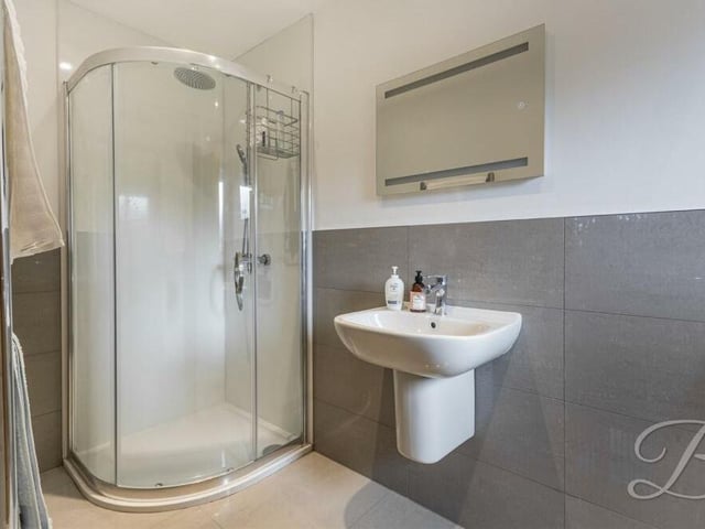 This is the second en suite shower room on the first floor of the Mansfield property. It consists of a shower cubicle with rainfall shower, a wall-mounted wash hand basin, low-level WC, tiled floor, chrome, heated towel-rail and ceiling spotlights.