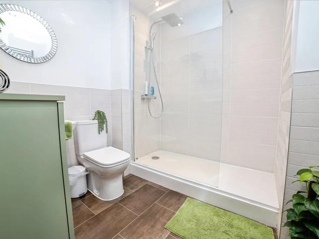 The stylish shower room features a heated towel rail, Shower, WC, wash hand basin, tiled flooring and part tiled walls.
