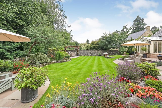 The rear garden contains seating areas, a lawn, a barbecue area and a wooden pergola.