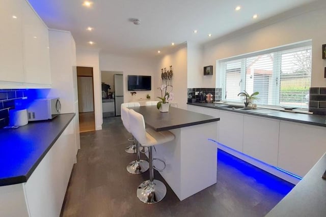 The first room to look at on our guided tour is the modern fitted kitchen. It includes a range of white wall and base units, with remote-controlled under-lighting, and a pleasant central island with cupboards underneath.
