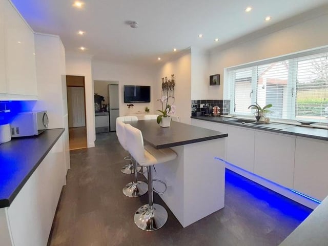 The first room to look at on our guided tour is the modern fitted kitchen. It includes a range of white wall and base units, with remote-controlled under-lighting, and a pleasant central island with cupboards underneath.