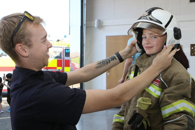 Firefighter Jenson Hallam helps Logan Hemingway into the fire kit.