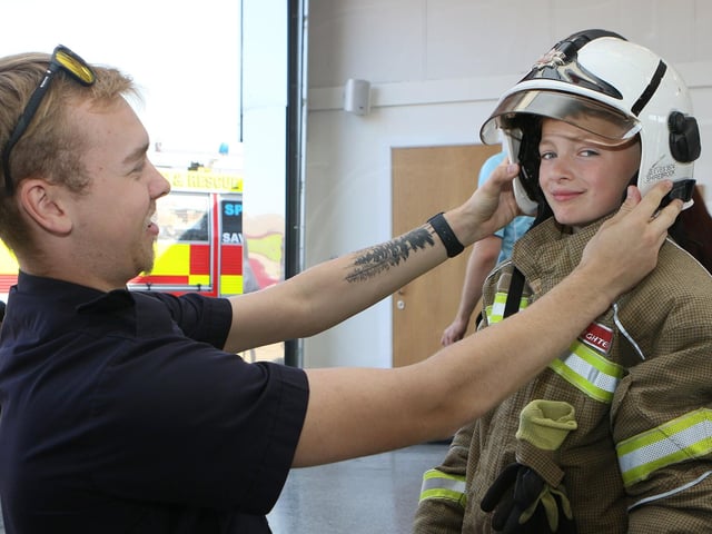 Firefighter Jenson Hallam helps Logan Hemingway into the fire kit.
