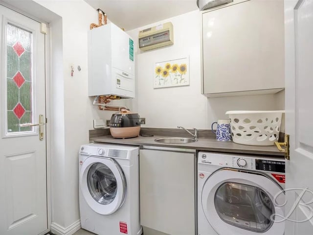 Completed with high gloss storage cupboards, work surfaces above, integrated sink, plumbing for appliances and a door for access to the side of the property.