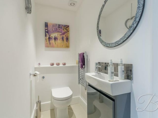 A contemporary toilet, comprising a low-flush WC, vanity hand wash basin, chrome, heated towel-rail and tiled flooring, is a handy addition to the ground floor.
