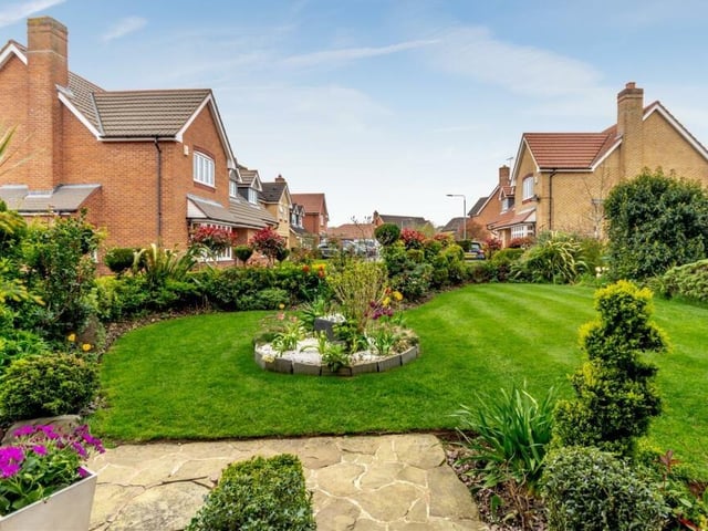 The front garden features a lawn and borders with plants, shrubs and pebbles, as well as LED floodlights.
