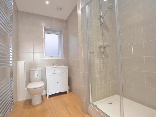 Here is the stylish shower room, which houses a contemporary three-piece suite with chrome fittings. There's a double-width, tiled shower enclosure, a vanity unit with inset wash hand basin, mixer tap and storage cupboard underneath, and a low-flush WC. Completing the room are a large floor-to-ceiling heated towel-rail, fully tiled walls and four ceiling spotlights.