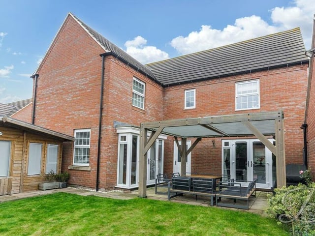 Let's step outside now to check out the stunningly landscaped garden at the back of the £550,000-plus property. This is a view of the rear of the house, with a sheltered pergola seating area in the foreground and a summer outbuilding to the left.