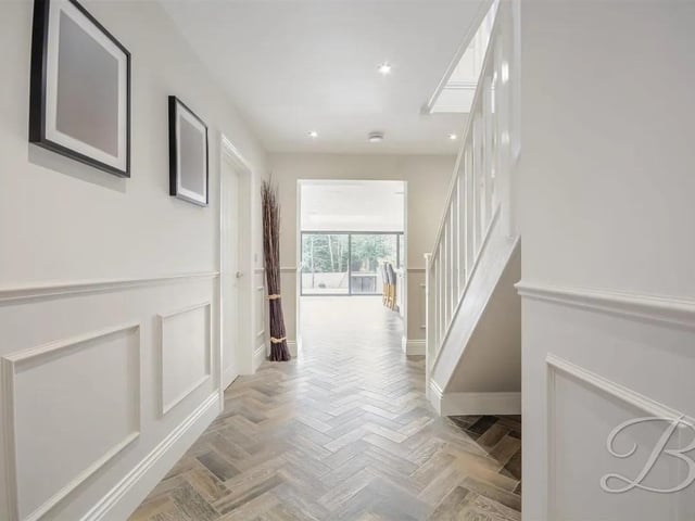 A stunning hallway featuring elegant herringbone flooring with underfloor heating, beautifully panelled walls, and ample space to showcase your furniture.