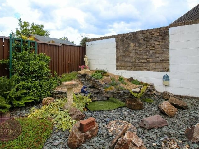 Features in the rear garden include gravel borders, an artificial lawn and a range of mature plants and shrubs.