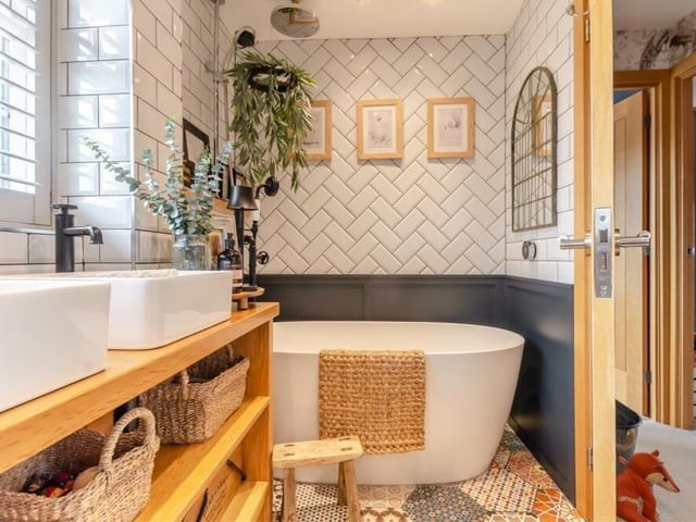 The family bathroom also features a free-standing bath tub with separate, floor-mounted swan-neck mixer tap and shower handset, plus an additional ceiling-mounted rainfall shower. Note also the hexagonal-patterned tiled floor and the herringbone tiled walls.