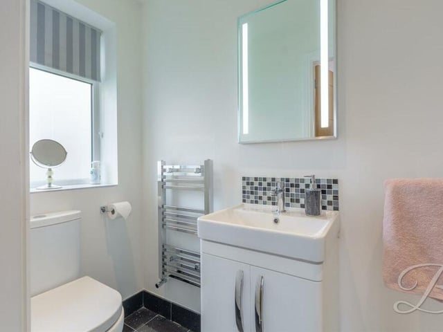 The second en suite shower room on the first floor of the Kirkby property. It is fitted with a walk-in shower cubicle, low-flush WC, vanity hand wash basin and chrome, heated towel-rail.