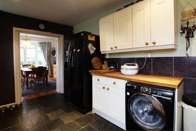 Here is another view of the kitchen, which has a country feel to it. The flooring is tiled and the ceiling is fitted with spotlights, while there are three double-glazed windows and a door leading to the outside of the property.