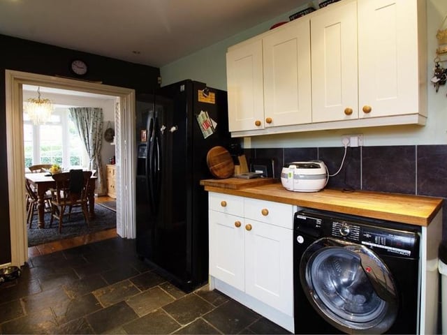 Here is another view of the kitchen, which has a country feel to it. The flooring is tiled and the ceiling is fitted with spotlights, while there are three double-glazed windows and a door leading to the outside of the property.