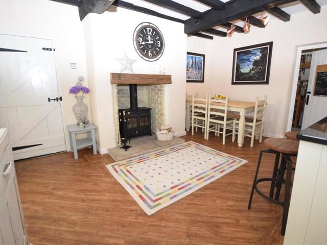 The large clock in the wall tells us it's time to step into the open-plan, country-style dining kitchen, which is beautifully designed, with a contemporary twist. At the heart of it is a feature fireplace that gives the room a cosy aura. It has an oak mantle and flagstone hearth. There is also ample space for a dining table and chairs.