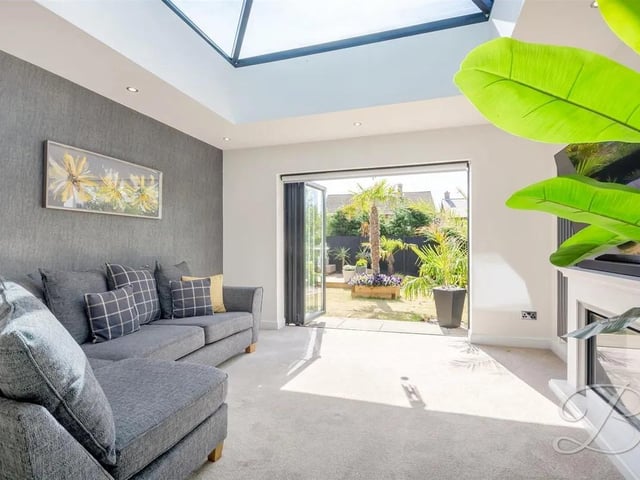 A bright sunroom offers additional living space along with another skylight, and bifolding doors—creating a perfect year-round retreat
