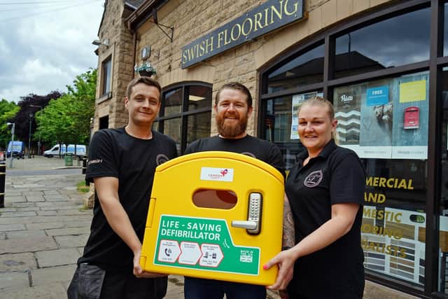Heart-attack survivor Karl Fisher (centre) with the defibrillator that will be installed outside his Swish Flooring carpet shop in Mansfield Woodhouse for public use. Karl is flanked his his sister, Keeley Fisher, who is the shop manager, and employee Tyler Jones.