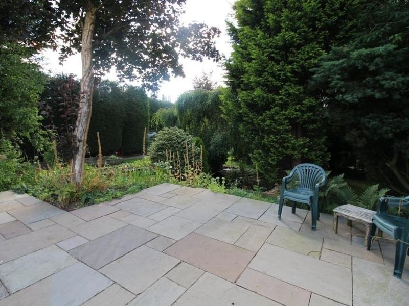 Let's take a look outside now and, nestled among the trees within the glorious garden, is this patio area with seating.