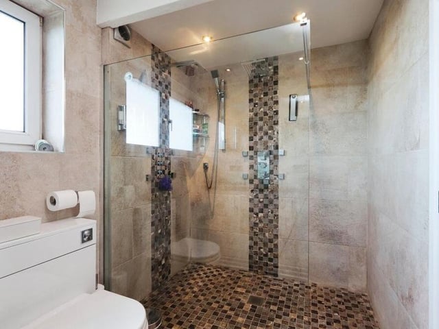 The main bedroom has access to this excellent en suite shower room. It features a double-walk-in shower, his and hers vanity sink unit and low-level WC.