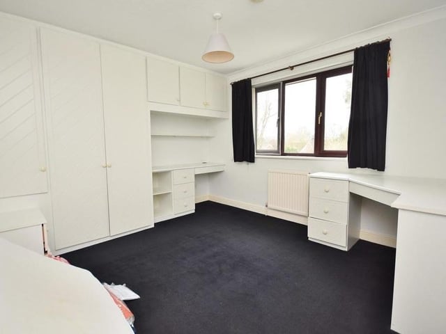 Like the master, the second bedroom includes built-in wardrobes and dressing table. A uPVC window overlooks the back of the house.