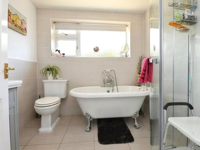 The family bathroom is fitted with a free-standing rolltop bath that has a mixer tap and shower hose. There's also a shower cubicle, wash hand basin vanity unit, WC, towel radiator, tiled floor and down spotlights.