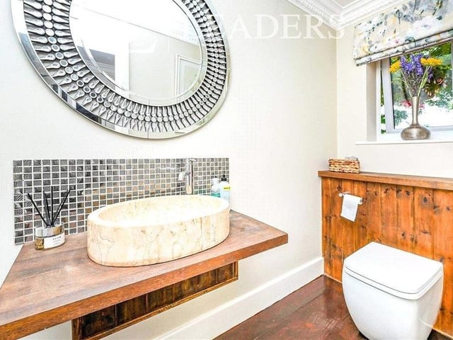 The ground floor also features this smart cloakroom, which is fitted with a white low-level WC, feature sink with travertine bowl, oak flooring and spotlights.